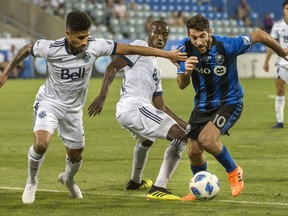 Montreal Impact's Ignacio Piatti, right, breaks away from Vancouver Whitecaps' Sean Franklin, left, and teammate Ali Ghazal during second half Canadian Championship action in Montreal on July 18, 2018.