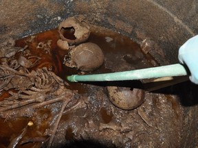 A handout picture released on July 19, 2018 by the Egyptian Antiques ministry shows skeletons in the black granite sarcophagus uncovered early this month in the Sidi Gaber district of Alexandria, filled with sewage water. Skeletons are believed to be three warriors as one of the skulls bear a wound resulted from the hit of an arrow. / AFP PHOTO / EGYPTIAN ANTIQUITIES MINISTRY / --/AFP/Getty Images