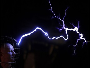 Oleg Melnik, wearing a wire helmet, getting electrical discharges of Tesla coil inside a Faraday cage at the Elemento Science Museum in Minsk in 2016. The Faraday cage blocks electromagnetic fields and was named for Michael Faraday, who invented it in the 19th century.