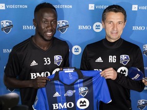 Montreal Impact's newest player, French international right-back Bacary Sagna, left, is given a team jersey by head coach Rémi Garde, in Montreal on Tuesday August 14, 2018.