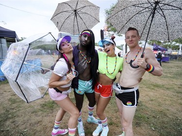Tina Desrochers, left, Toshiro Arthur, Giulia Tripoli and Jak Barradell keep umbrellas handy during the frequent downpours during Pride festivities in Montreal on Friday, August 17, 2018.  The four were manning the MAC cosmetics booth.
