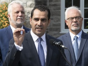 Monsef Derraji is flanked by Quebec Premier Philippe Couillard, left, and Quebec Finance Minister Carlos Leitão during the official nomination announcement in Pierrefonds on Tuesday.