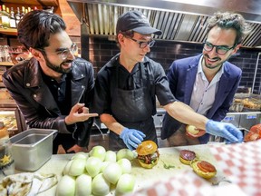 Burger Week founders Na'eem Adam, left, and Thierry Rassam, right, flank cook Alex Rosette at Notre-Boeuf-de-Grâce in Montreal on Monday. Their choices were L’Orozco (beef with avocado, cheese curds and homemade chimichurri) and the self-explanatory Thou Shalt Bacon Cheeseburger: Death.