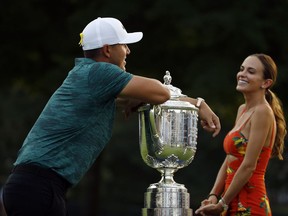 Brooks Koepka leans on the Wanamaker Trophy as he talks with his girlfriend, Jena Sims, after winning the PGA Championship golf tournament at Bellerive Country Club, Sunday, Aug. 12, 2018, in St. Louis.