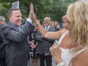 Coalition Avenir Québec Leader François Legault high-fives Denise Coderre after speaking with her about financial assistance for those caring for relatives with disabilities on Aug. 26 in Terrebonne. THE CANADIAN PRESS/Peter McCabe