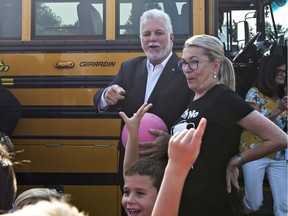 Quebec Liberal Leader Philippe Couillard calls on kids to play ball in St-Félicien on Monday, Aug. 27, 2018, as he arrives at a news conference to announce his education program. Couillard's wife, Suzanne Pilote, right, looks on.