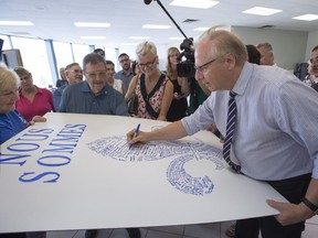 PQ Leader Jean-François Lisée signs a poster while campaigning at the party's local riding office in Terrebonne, Monday, August 27, 2018.