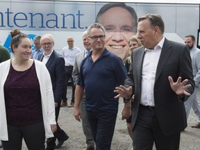 Coalition Avenir Québec leader François Legault, right, chats with owner Ivanhoe Brochu and his daughter, Oceane, while visiting a fruit and vegetable producer on Aug. 30, 2018, in St-Henri, Que.