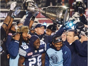 Toronto Argonauts head coach Marc Trestman, centre, and players celebrate with the Grey Cup after defeating the Calgary Stampeders in CFL football action in the 105th Grey Cup on Sunday, Nov. 26, 2017 in Ottawa.