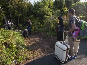 RCMP officers speak with migrants as they prepare to cross the U.S.-Canada border illegally near Hemmingford, Que.