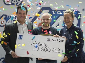 Jérémie Gagnon, 23, of Bas-Saint-Laurent, centre receives a cheque of $33,600,463 from Loto-Québec officials Richard Trudel and Julie Houle, after winning the Lotto 6/49 jackpot Friday, August 31, 2018 in Quebec City.