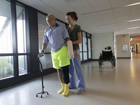 William Lytton, of Scarsdale, N.Y., left, is assisted by physical therapist Caitlin Geary at Spaulding Rehabilitation Hospital, in Boston, Tuesday, Aug. 28, 2018, while recovering from a shark attack. Lytton suffered deep puncture wounds to his leg and torso after being attacked by a shark on Aug. 15 while swimming off a beach, in Truro, Mass. Lytton injured a tendon in his arm while fighting off the shark.