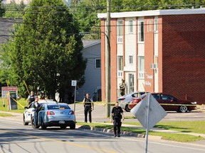 Police and RCMP officers survey the area of a shooting in Fredericton, N.B., on Friday, August 10, 2018.