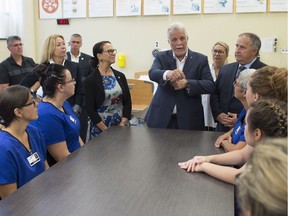 Quebec Liberal Leader Philippe Couillard, centre, speaks to students while visiting an auxiliary nursing school, Thursday, August 30, 2018, in Saint-Georges Que. Liberal candidate for Jean-Lesage, Gertrude Bourdon, left, and Beauce-Sud candidate Paul Busque, right, look on.