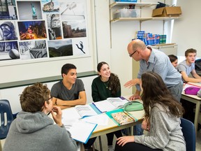 A group of St. George's high school students engage with each other and their teacher during a French class.