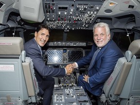 Prime Minister Justin Trudeau, left, and Quebec Premier Philippe Couillard sit in a flight simulator during a visit to CAE in Montreal on Wednesday.