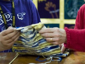 A volunteer teaches knitting techniques to a high school student: In several schools, elders run the breakfast club, help with reading circles and extra-curricular activities such as the knitting and chess clubs, Don Rosenbaum writes.