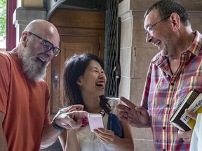 Pastoral speaker Yves Cote, left, and Father Philippe Morinat share a laugh with write Kim Thuy inside a Montreal church.