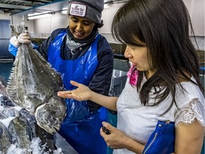 Montreal writer Kim Thuy and worker Mariam Idle look over a halibut at Poissonnerie La Mer, an indoor market.