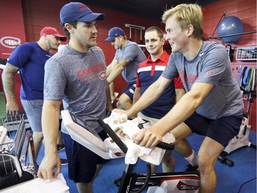 Andrew Shaw, front left, talks with Artturi Lehkonen as he rides the stationary cycle while Nicolas Deslauriers, left rear, checks in with Karl Alzner on the first day of Canadiens' training camp at the Bell Sports Complex in Brossard on Thursday, Sept. 13, 2018.  Athletic therapist Jean-Luc Gohier supervises Lehkonen's performance.
