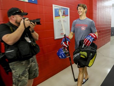 First round draft choice Jesperi Kotkaniemi smiles at photographers while carrying some gear on the way to have photos taken on the first day of the Canadiens' training camp at the Bell Sports Complex in Brossard on Thursday, Sept. 13, 2018.