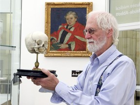 Pathologist and professor Rick Fraser handles a display of a human skull at the Maude Abbott Medical Museum at McGill University, as Maude Abbott — the museum's curator for 25 years beginning in 1898 — looks on from her portrait.