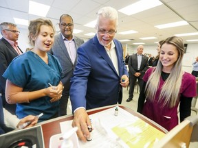 Quebec Premier Philippe Couillard talks with Université de Montréal nursing student Annabelle L. St-Pierre, left, and Ariane Champagne while campaigning in Laval, north of Montreal Monday September 24, 2018.