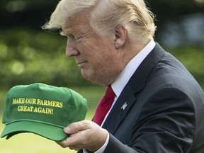 US President Donald Trump displays caps reading "Make our Farmers Great Again" while walking to board Marine One as he departs the White House in Washington, DC, on August 30, 2018 for Indiana.