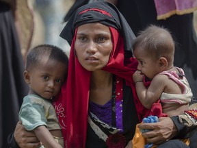 FILE - In this Sunday, Oct. 22, 2017, file photo, a Rohingya Muslim woman, Rukaya Begum, who crossed over from Myanmar into Bangladesh, holds her son Mahbubur Rehman, left and her daughter Rehana Bibi, after the government moved them to newly allocated refugee camp areas, near Kutupalong, Bangladesh. A team of independent investigators examining alleged violence and killings in Myanmar that caused hundreds of thousands of Rohingya Muslims to flee their homes have issued a searing critique of the United Nations' own operations in the country just as bloodshed erupted in August 2017.