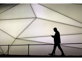 A man looks at his phone as he walks along the Samsung stand during the Mobile World Congress wireless show in Barcelona, Spain, on February 27, 2017. Smartphone users will be able to download a free app by the end of the month to ramp up the security of their device. The digital app, created by a newly formed cybersecurity collective out of Montreal, is designed to help users detect security breaches and scamming attempts in their emails, texts and other apps, as well as give tips to prevent future hacks.