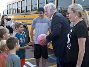 Philippe Couillard encourages kids to play ball in St-Félicien as he arrives at a news conference to announce the Liberals' education program on Monday, August 27, 2018. Couillard's wife, Suzanne Pilote, looks on.