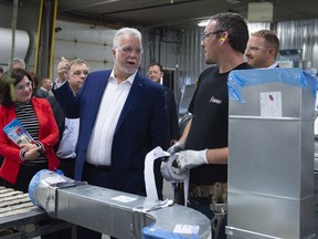 Local candidate Veronique Tremblay, left, looks on as Quebec Liberal Leader Philippe Couillard, centre, visits a ventilation shop in Quebec City on Friday, Sept. 28, 2018.