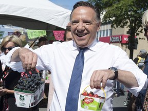 Coalition Avenir Quebec Leader Francois Legault jokingly uses strawberries and grapes, saying "let's go from red to blue" while campaigning, Sept. 8, 2018, in Quebec City.