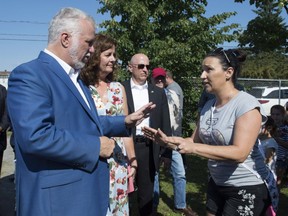 Quebec Liberal Leader Philippe Couillard, left, is criticized for the health system by a woman as he visits a flea market, Saturday, Sept. 15, 2018, in Quebec City. Local candidate Marie-France Trudel, behind, also listens.