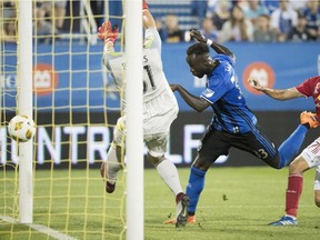 Montreal Impact's Bacary Sagna, centre, scores against New York Red Bulls goalkeeper Luis Robles during first half MLS soccer action in Montreal on Sept. 1, 2018.