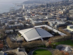 FILE - In this Dec. 4, 2017, file photo, the iconic sloped roof of KeyArena, center, a sports and entertainment venue at the Seattle Center, is seen in an aerial photo in Seattle. Seattle is moving ahead with efforts to renovate the aging city-owned KeyArena into a premier venue that could be ready for an NBA or NHL team within three years.
