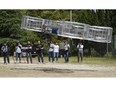 FILE - In this Saturday, June 3, 2017, file photo, Tsubasa Nakamura, project leader of Cartivator, third from left, watches the flight of the test model of the flying car on a former school ground in Toyota, central Japan. The Japanese government has started a "flying car" project, bringing together more than a dozen companies, including All Nippon Airways, electronics company NEC, Toyota-backed startup Cartivator and Uber, the ride-hailing service. Toyota and its group companies have also invested 42.5 million yen ($375,000) in a Japanese startup, Cartivator, that is working on a flying car.