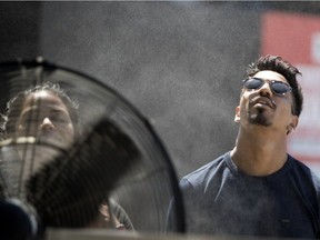 MONTREAL, QUE.: JULY 3, 2018-- Xavier Selly cools down in front of a large fan that is equipped with a water misting ring at the Montreal International Jazz Festival as Montreal endures a heat wave on Tuesday July 3, 2018. (Allen McInnis / MONTREAL GAZETTE) ORG XMIT: 60989