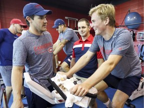 Montreal Canadiens' Andrew Shaw, front left, talks with Artturi Lehkonen as he rides a stationary cycle on the first day of training camp at the Bell Sports Complex in Brossard on Sept. 13, 2018. Athletic therapist Jean-Luc Gohier supervises Lehkonen's performance.