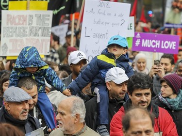 Two boys hold hands while sitting on their fathers' shoulders during an antiracism demonstration in Montreal on Sunday, Oct. 7, 2018.