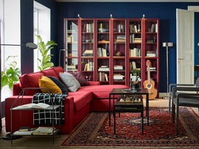 A row of three red bookcases create a colourful backdrop and offers much needed storage in a family room. Billy Bookcase with Glass Doors, $199 each, Ikea.com.