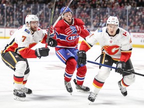 Jesperi Kotkaniemi tries to get to the net between TJ Brodie, left, and Mikael Backlund of the Calgary Flames during first period in Montreal Tuesday, Oct. 23, 2018.