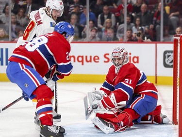 Carey Price makes a save as defenceman Mike Reilly holds off Calgary Flames Elias Lindholm during second-period action in Montreal Tuesday, Oct. 23, 2018.