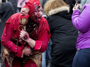 A zombie poses for pictures and tries to scare kids lining Peel St. during the annual Zombie Walk in Montreal on Saturday, Oct. 27, 2018.
