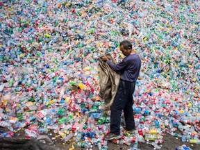 A Chinese labourer sorts plastic bottles for recycling on the outskirts of Beijing. "Disposable water bottles are a scourge, a scam and an environmental menace," writes T'Cha Dunlevy.