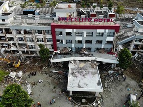 TOPSHOT - French member of the International Emergency Firefighters and locals search for survivors in the badly damaged Mercure hotel in Palu in Indonesia's Central Sulawesi on October 4, 2018, following the September 28 earthquake and tsunami. - A total of 1,424 people have been confirmed dead and over 2,500 injured after the monster earthquake struck, sending destructive waves barrelling into Sulawesi island.