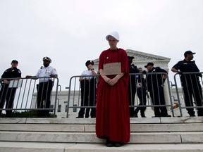 TOPSHOT - Payton Sander wearing a dress from The Handmaid's Tale protests at the steps of the US Supreme Court to protest against the appointment of Supreme Court nominee Brett Kavanaugh in Washington DC, on October 6, 2018.
