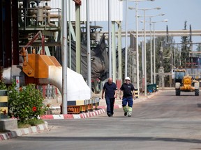 Two Palestinian operators walk inside the Gaza power plant in Nuseirat, in the central Gaza Strip October 9, 2018. - Trucks carrying Qatari-bought fuel entered the Gaza Strip on October 9 to help power the Palestinian enclave's only power station. An agreement reached between the United Nations, Qatar, Israel and Gaza's Islamist rulers Hamas is expected to see the small Gulf state pay for tens of millions in fuel in the coming months to help reopen the power station.