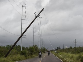 Residents ride their motorcycles past fallen electric poles near the Mexican fishing village of Teacapan in the wake of Hurricane Willa this week.