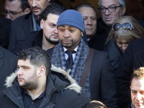 Mourners, including Gregory Woolley , centre in wool cap, leave the funeral Monday, December 30, 2013, for Montreal Mafia leader, Vito Rizzuto, at Notre-Dame-de-la-Defense Church, in Montreal's Little Italy district.